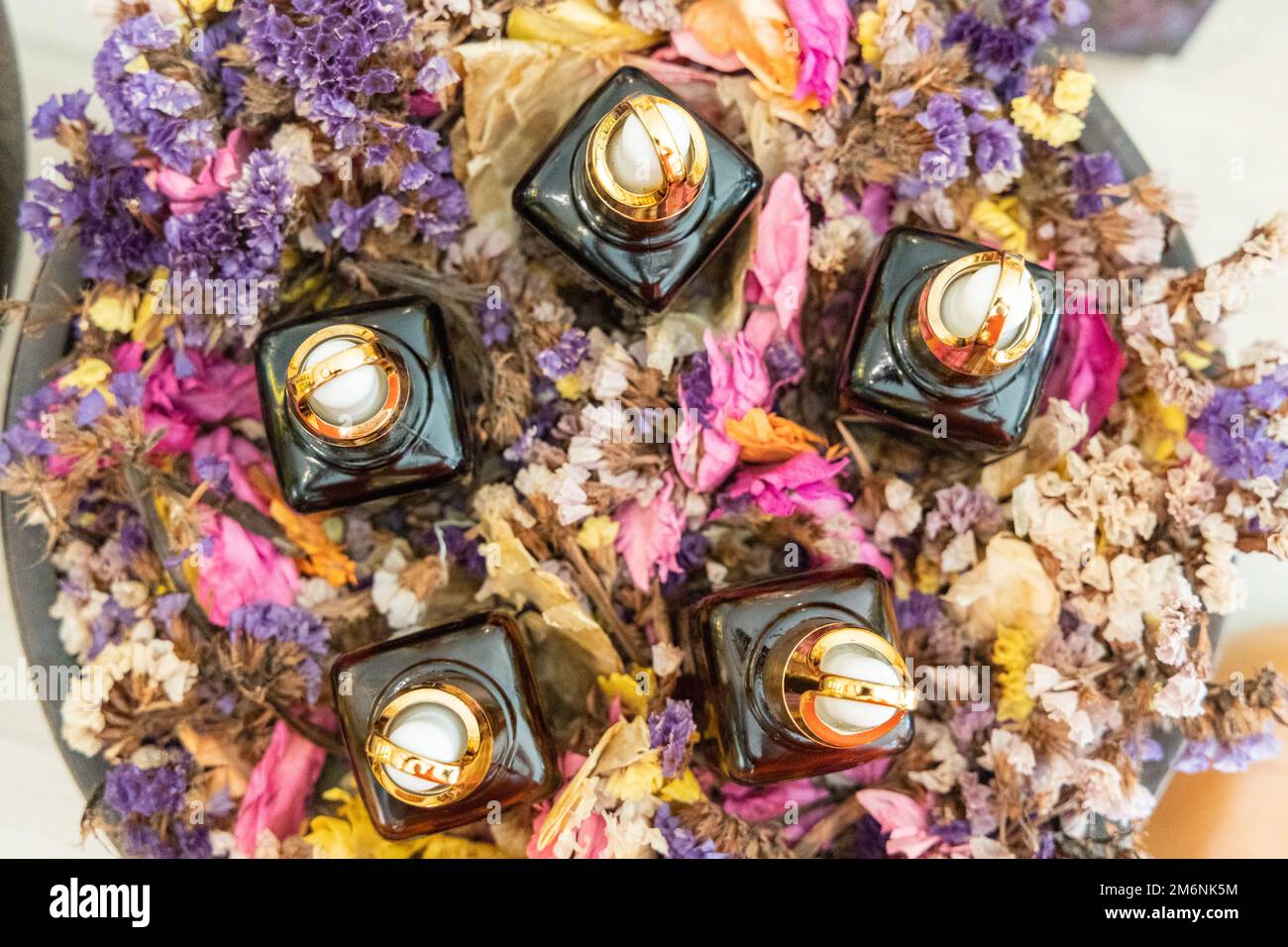 Vari dispenser di olio essenziale su vassoio circondato da petali di rosa per massaggi e spa Foto Stock