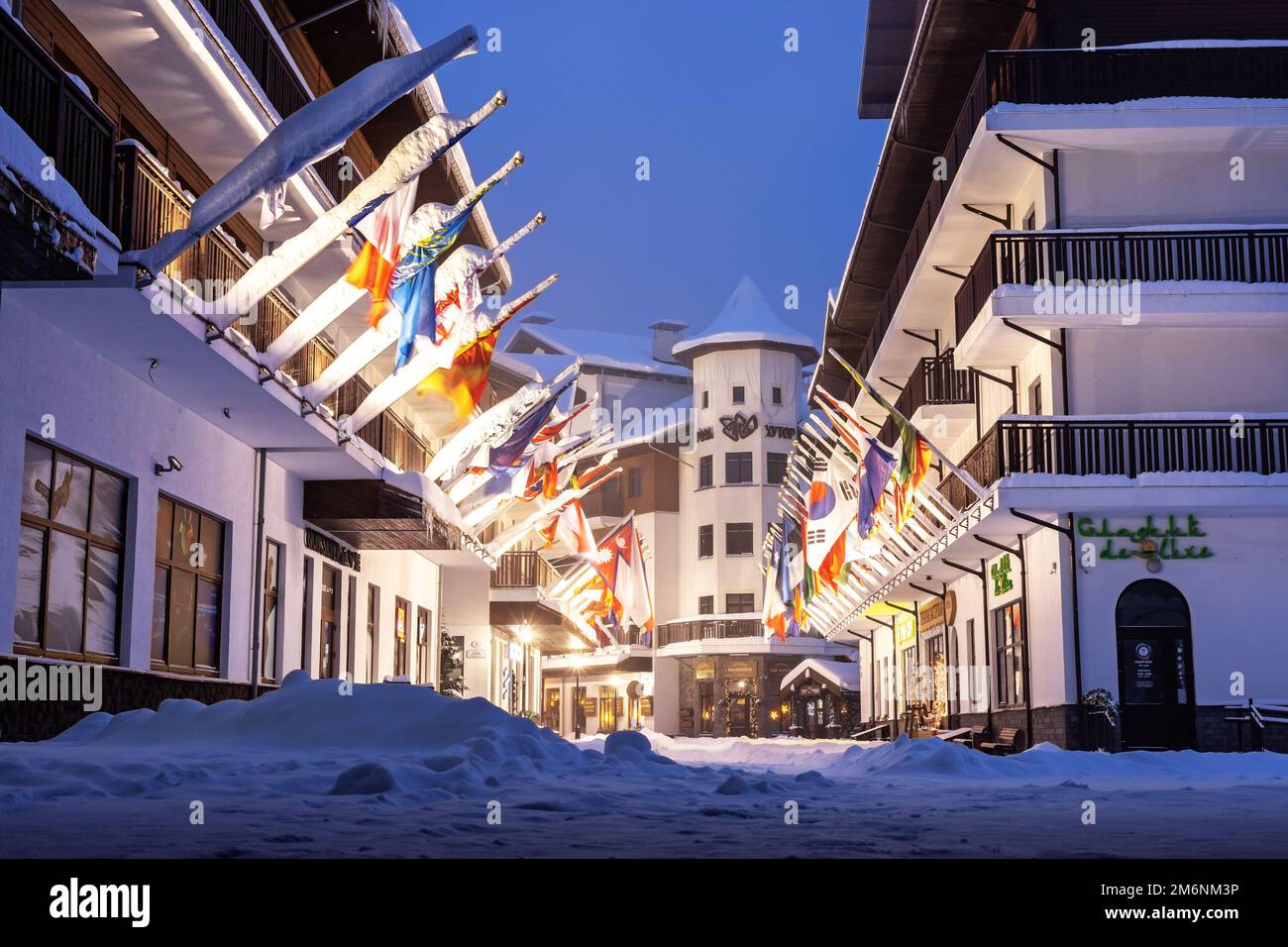 Russia, Sochi 22.12.2021. Vicolo di bandiere nel villaggio olimpico di notte d'inverno. Olympic Alley of Flags in illuminazione serale Foto Stock