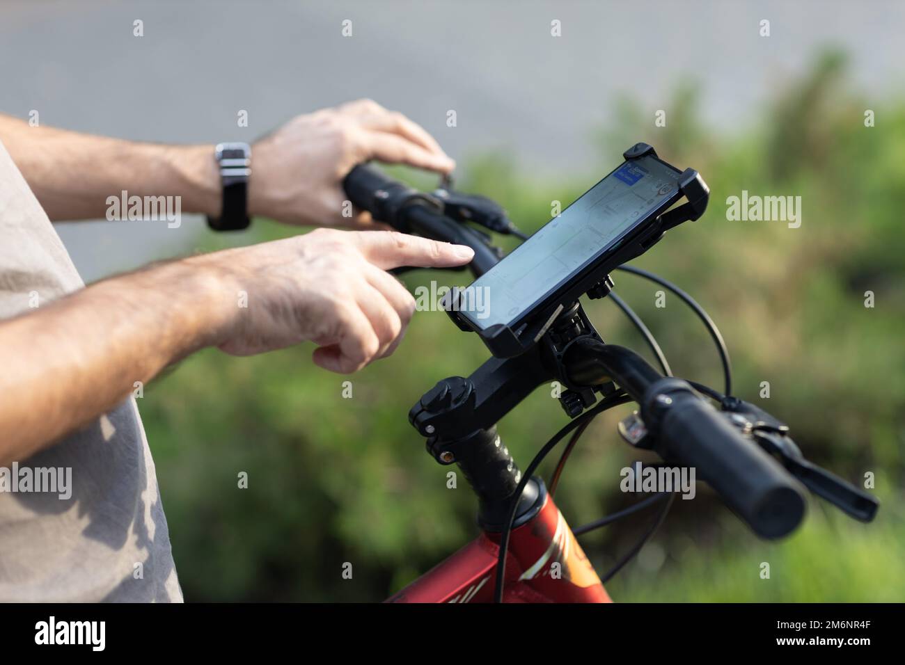 Uomo che pianifica il percorso utilizzando l'applicazione di navigazione GPS nel telefono cellulare sulla sua bicicletta. Foto Stock