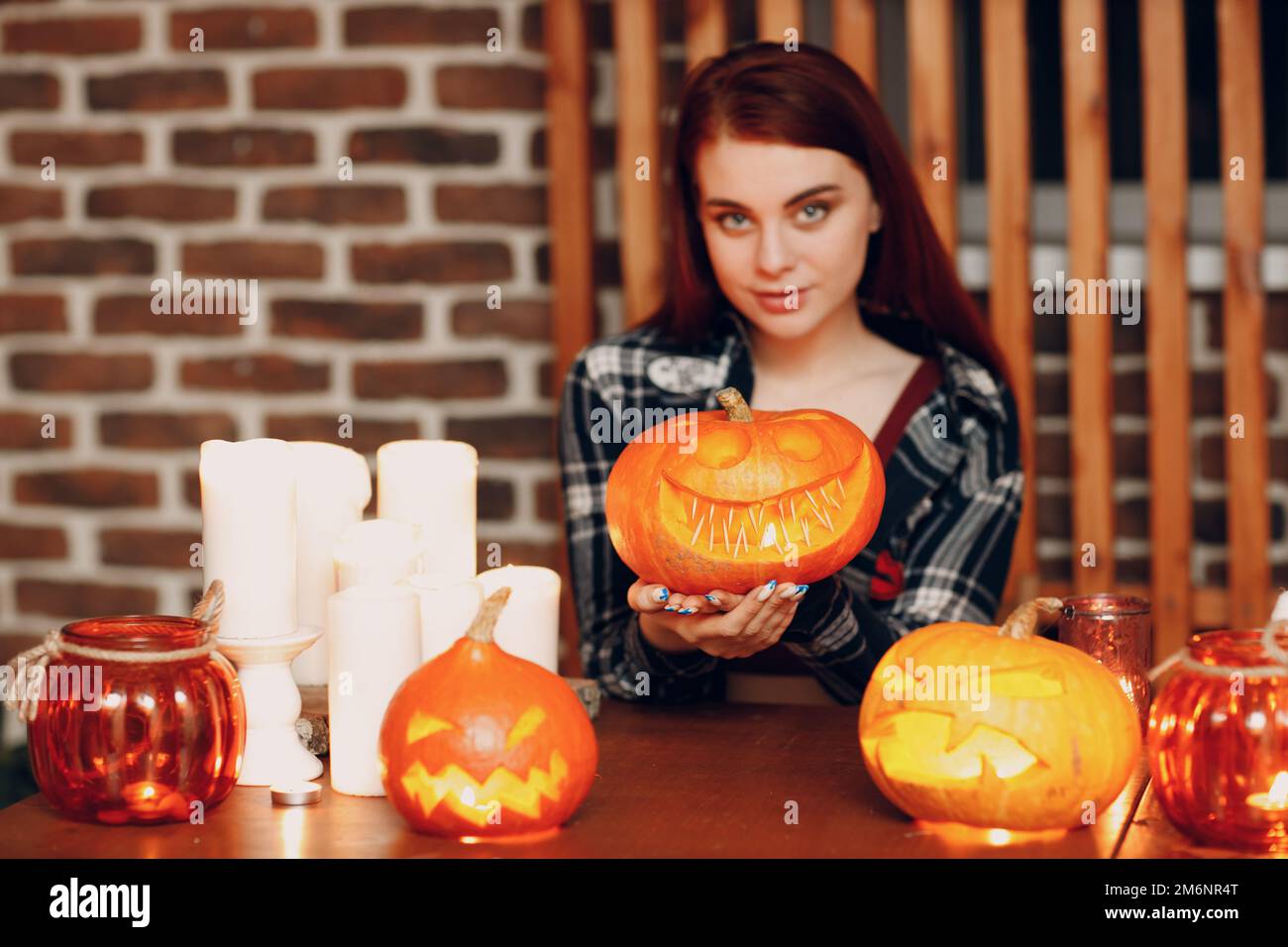 Giovane donna che fa Halloween zucca Jack-o-lanterna. Le mani femminili tagliano le zucche con il coltello. Foto Stock