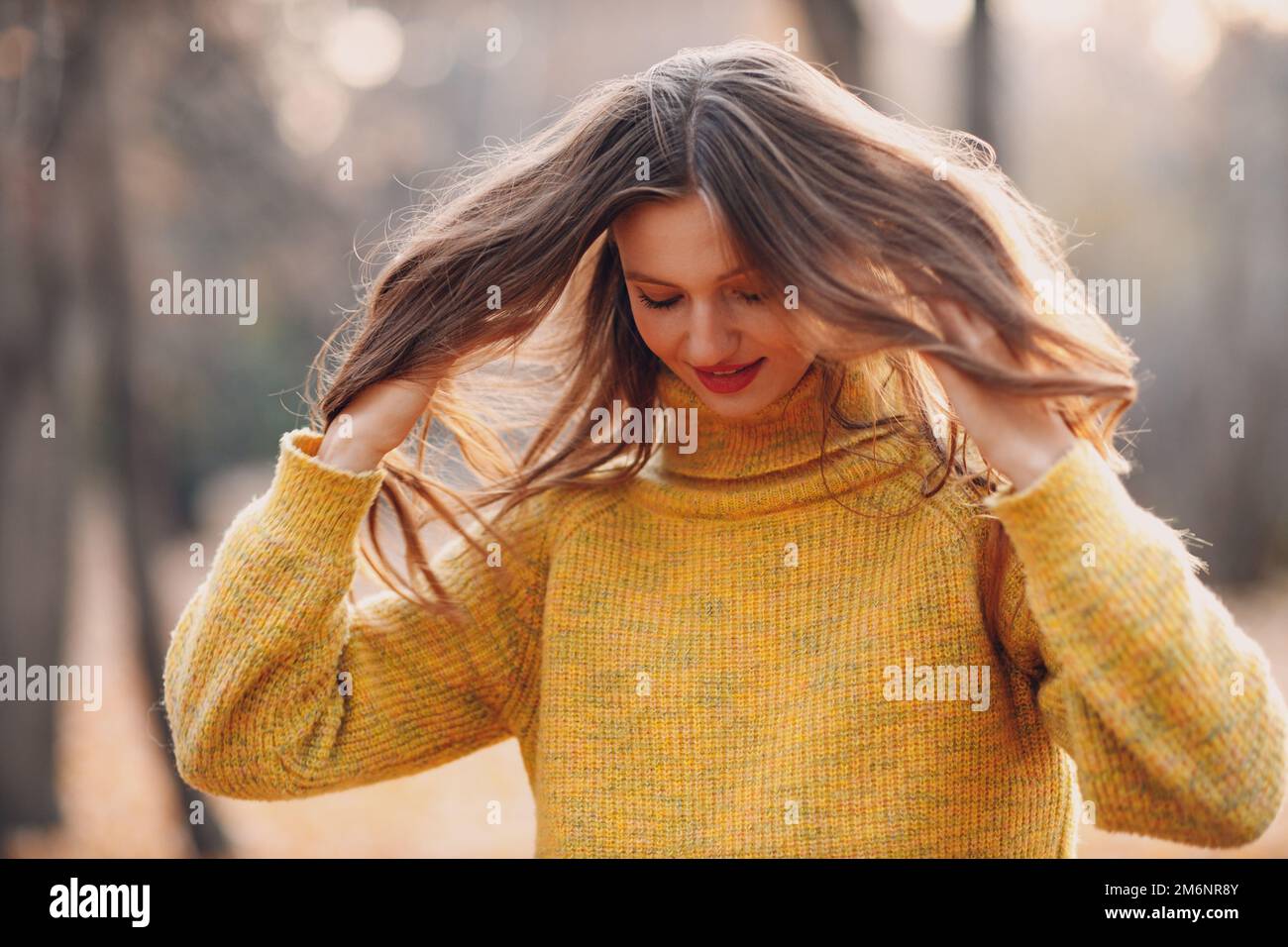 Giovane donna modello in autunno parco con foglie di acero giallo fogliame. Moda stagione autunnale. Foto Stock