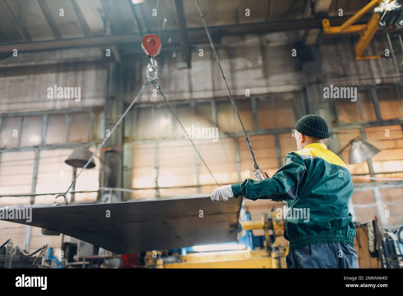 Sollevare la lamiera di metallo con paranco a catena con telecomando e gancio presso lo stabilimento industriale. Foto Stock