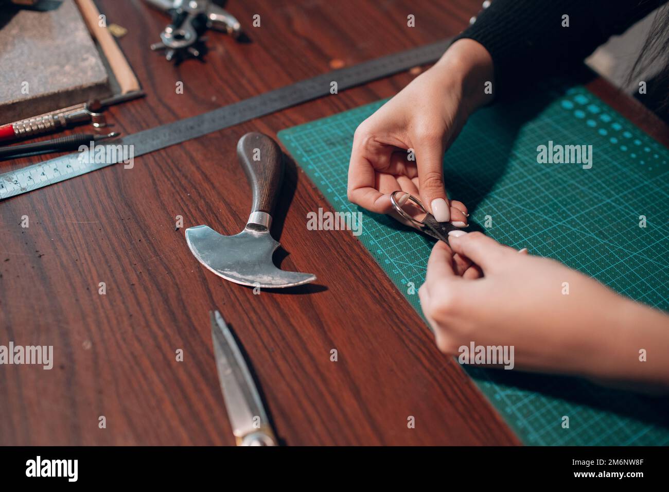 Tanner donna che fa articoli in pelle in officina. Processo di lavorazione del cuoio artigiano Foto Stock