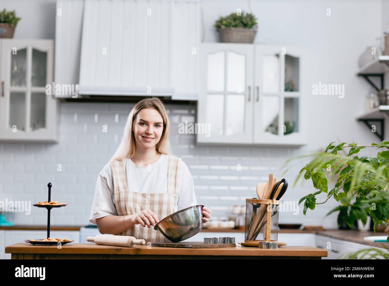 Pasticciere chef giovane donna caucasica con piatto da cucina sul tavolo da cucina. Dolci preparazione dessert. Foto Stock