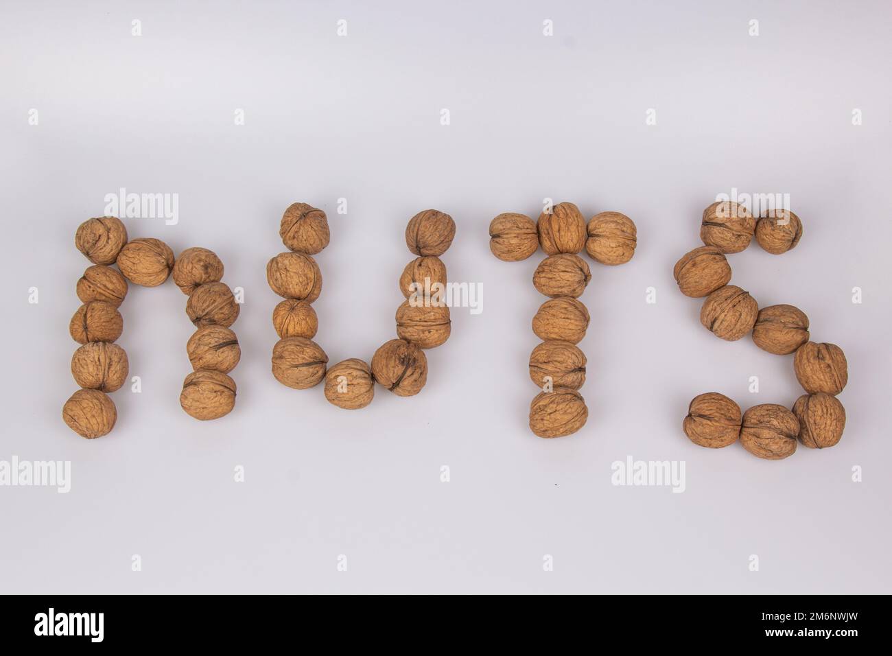 Nuts - un'iscrizione fatta di noci isolate su sfondo bianco. Vista dall'alto, disposizione piatta Foto Stock