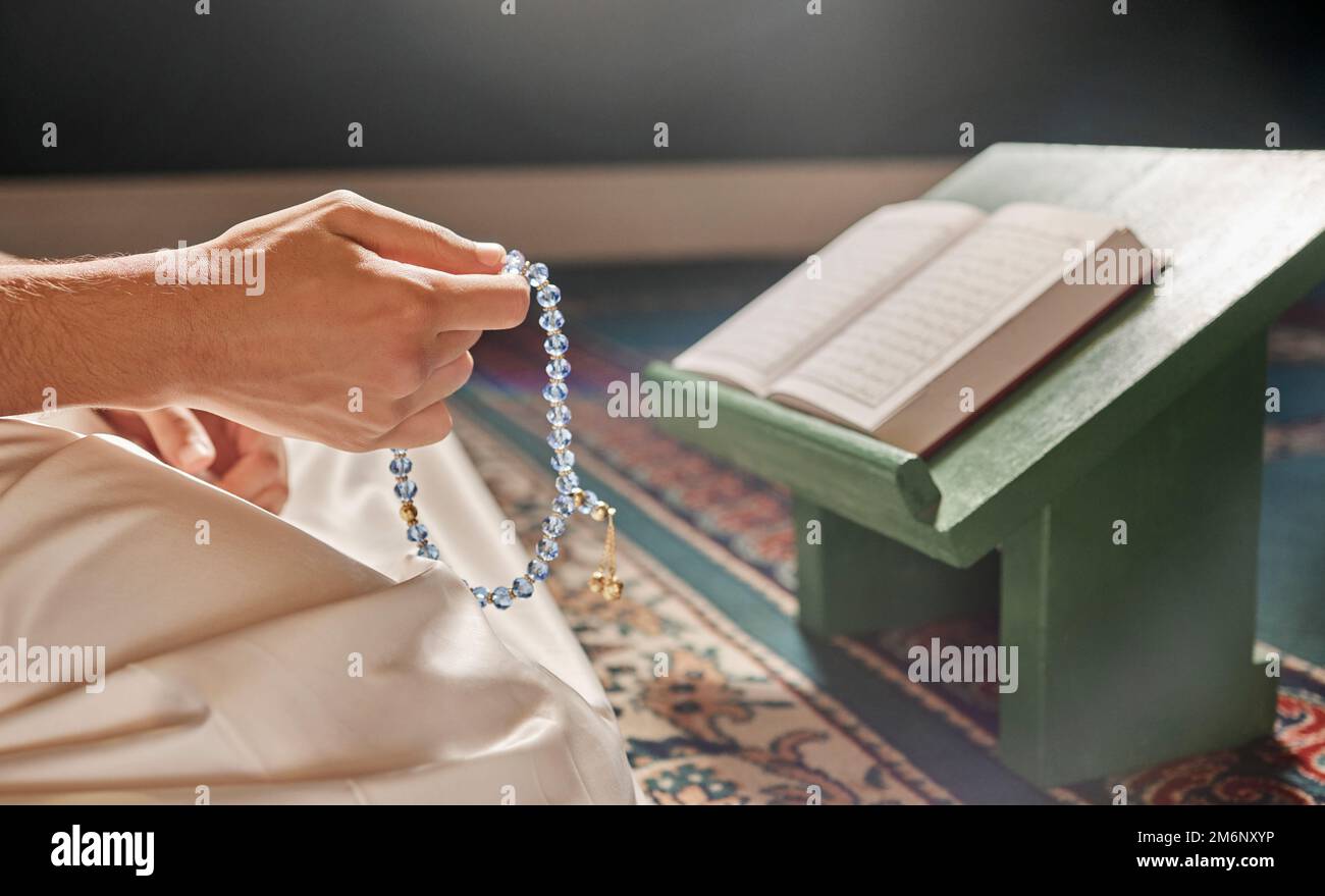 Quran, perline o mani che pregano nella religione islamica o musulmana ad Allah per la pace spirituale o la libertà nella moschea in Qatar. Musulmani pregano, leggendo o persona Foto Stock