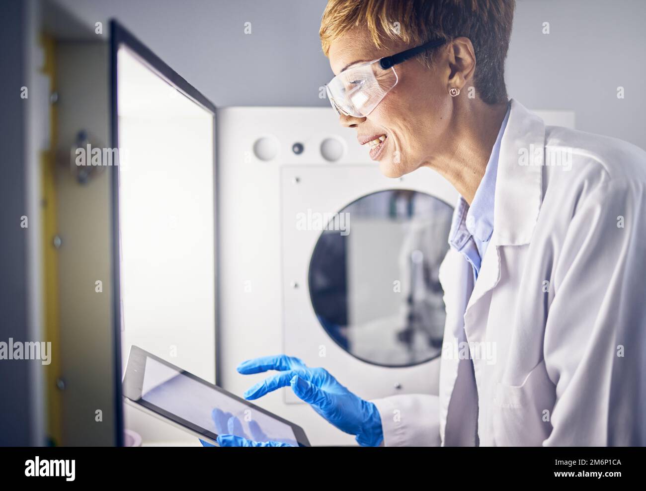 Donna anziana, scienziato e tablet in laboratorio per la ricerca, innovazione scientifica con risultati digitali e studio scientifico. Incubatore, esperimento e. Foto Stock