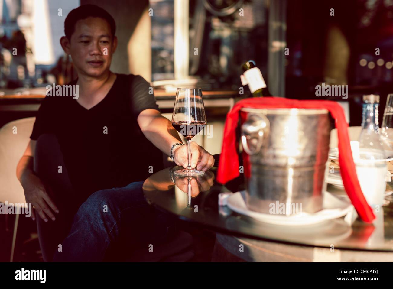 Buon uomo asiatico che beve vino rosso al ristorante. Foto Stock