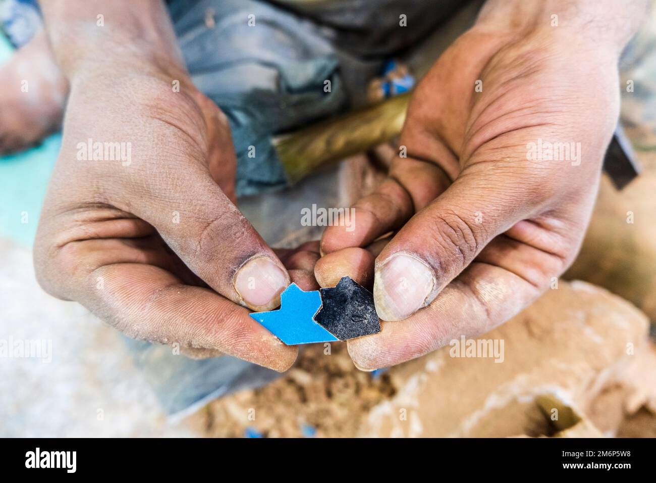 Artigiano che mostra piccole piastrelle di ceramica fatte a mano che si adattano perfettamente a vicenda in fabbrica di ceramica a Fez, Marocco, Nord Africa Foto Stock