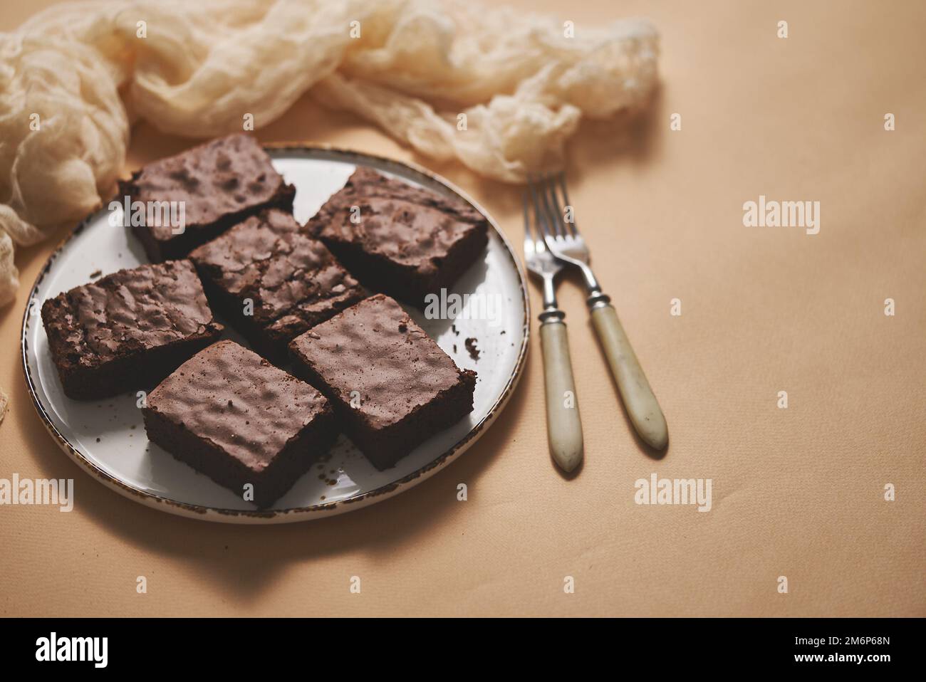 Brownie al cioccolato fatte in casa servite su un piatto bianco su sfondo beige Foto Stock