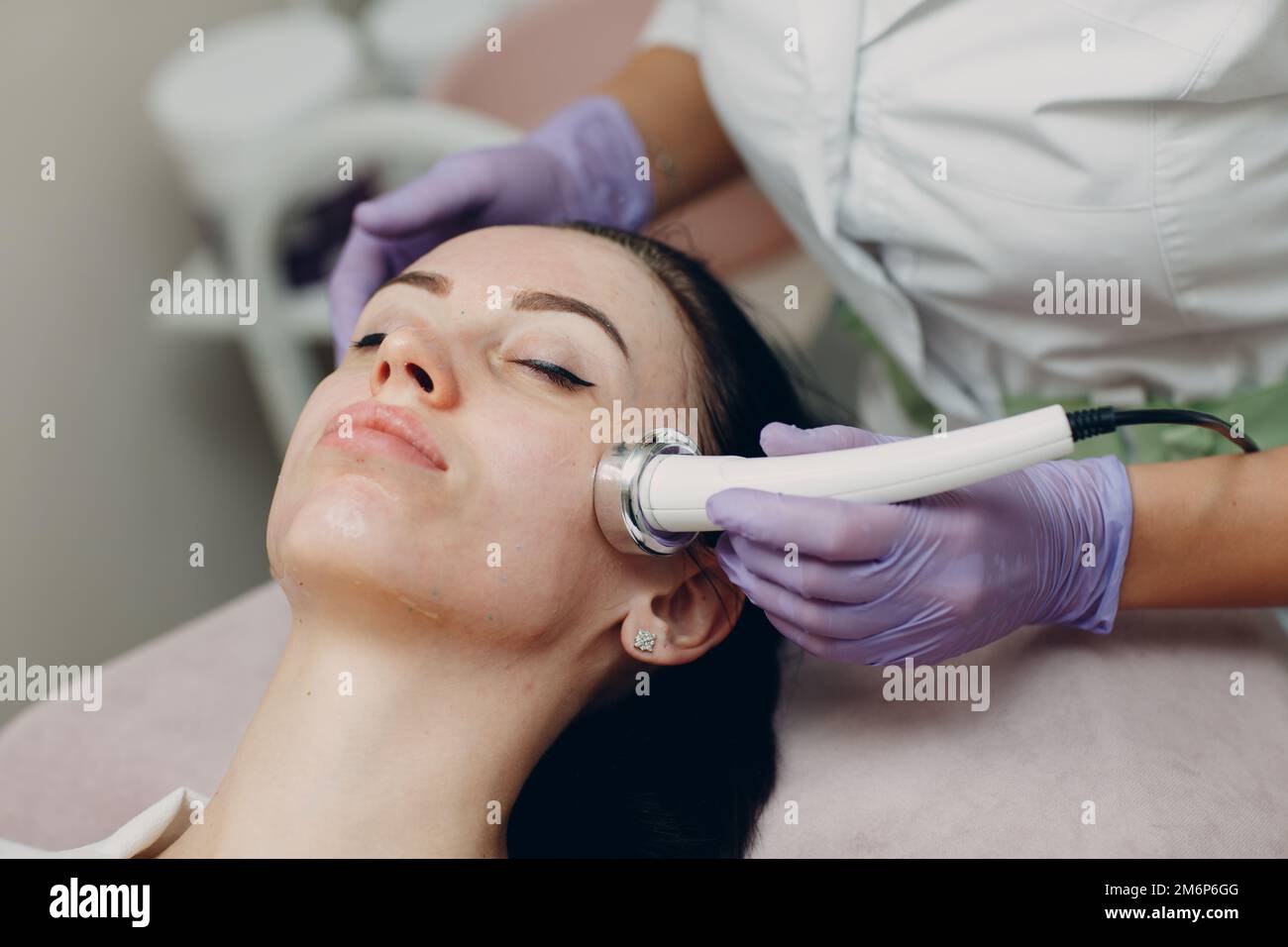 Primo piano della donna di testa che riceve la terapia facciale di phonoforesis di elettroporazione al salone di bellezza di centro termale. Foto Stock