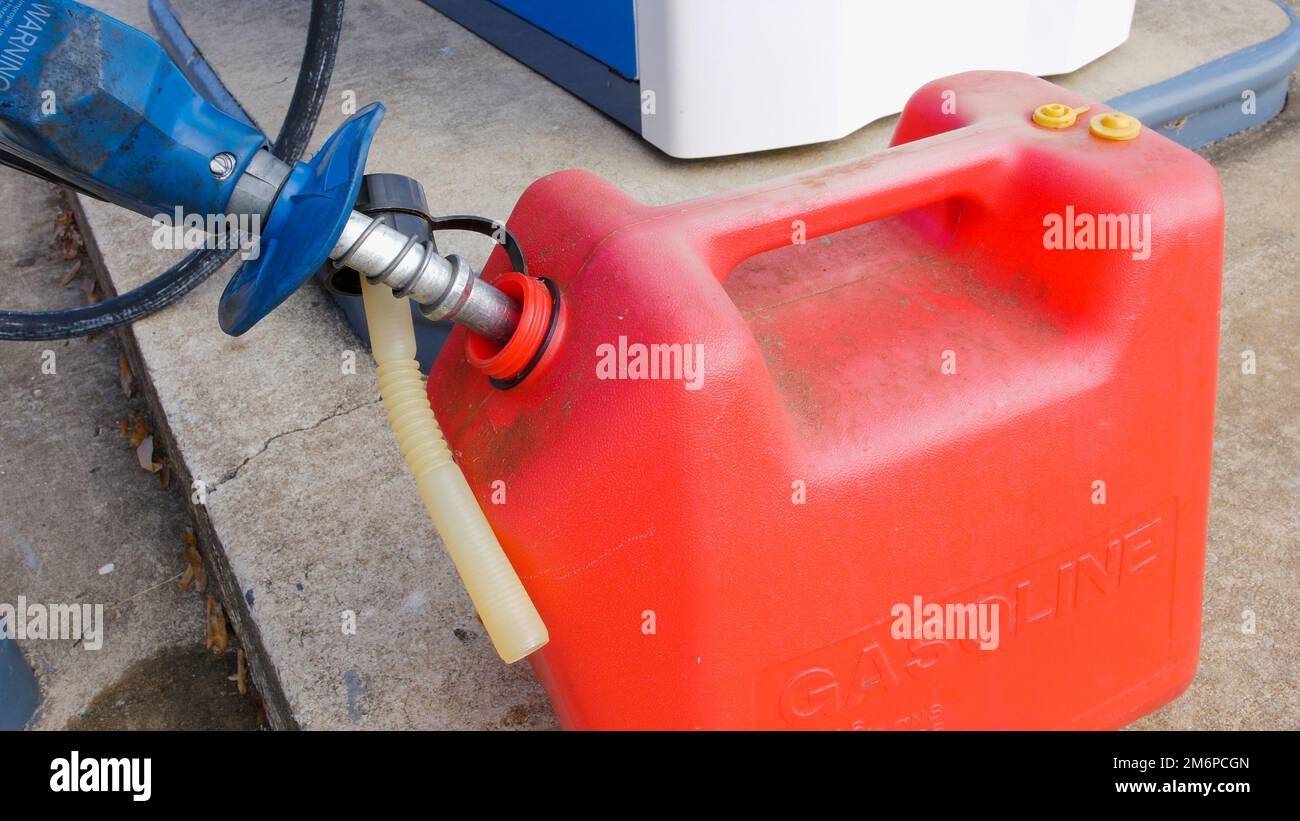 Rifornimento di benzina. Ugello della pompa di rifornimento e contenitore del carburante rosso presso la stazione di rifornimento carburante. Foto Stock