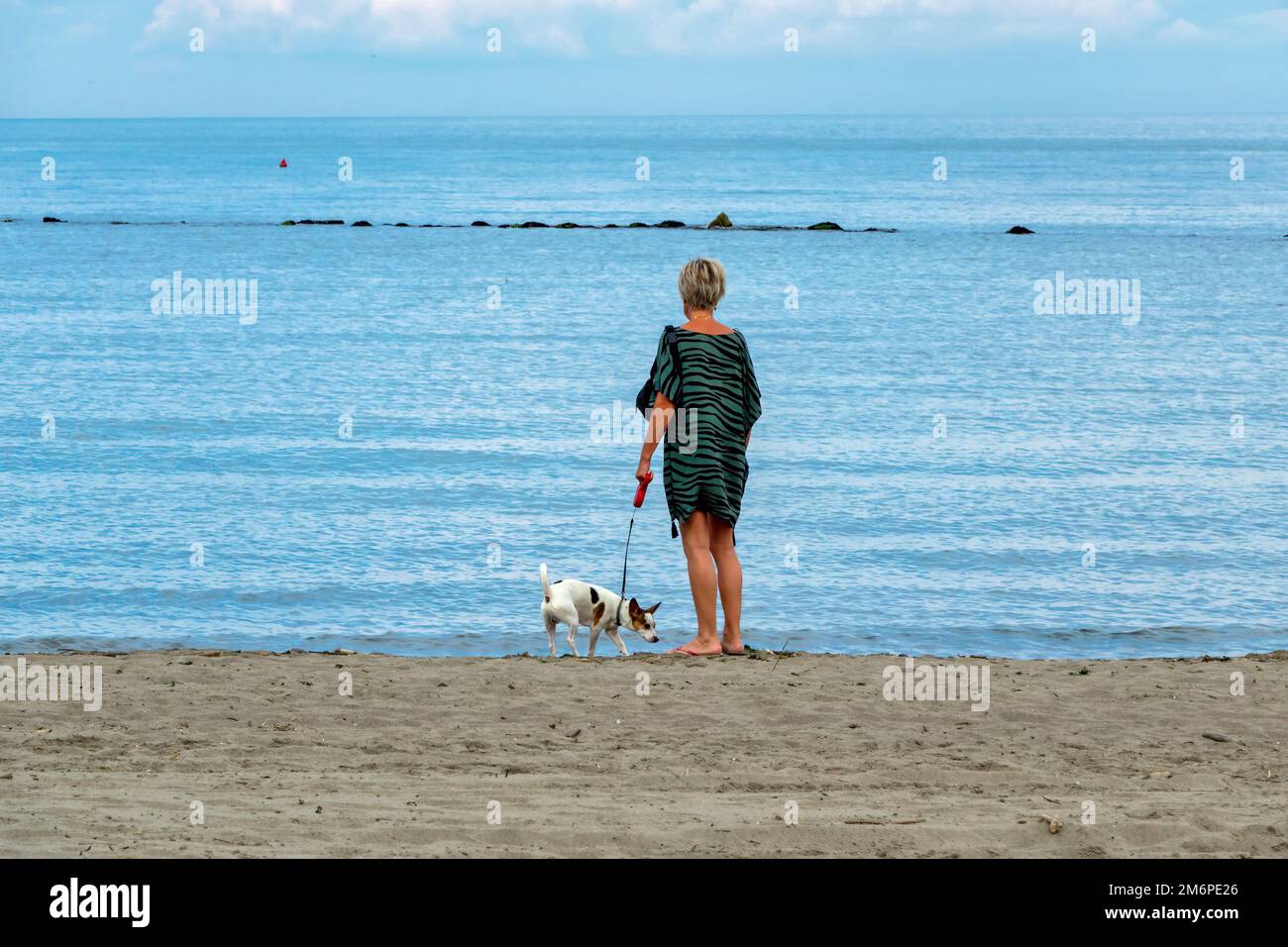 06 giugno 2021 Chioggia, Italia: Donna solitaria con il cane che guarda il mare Foto Stock