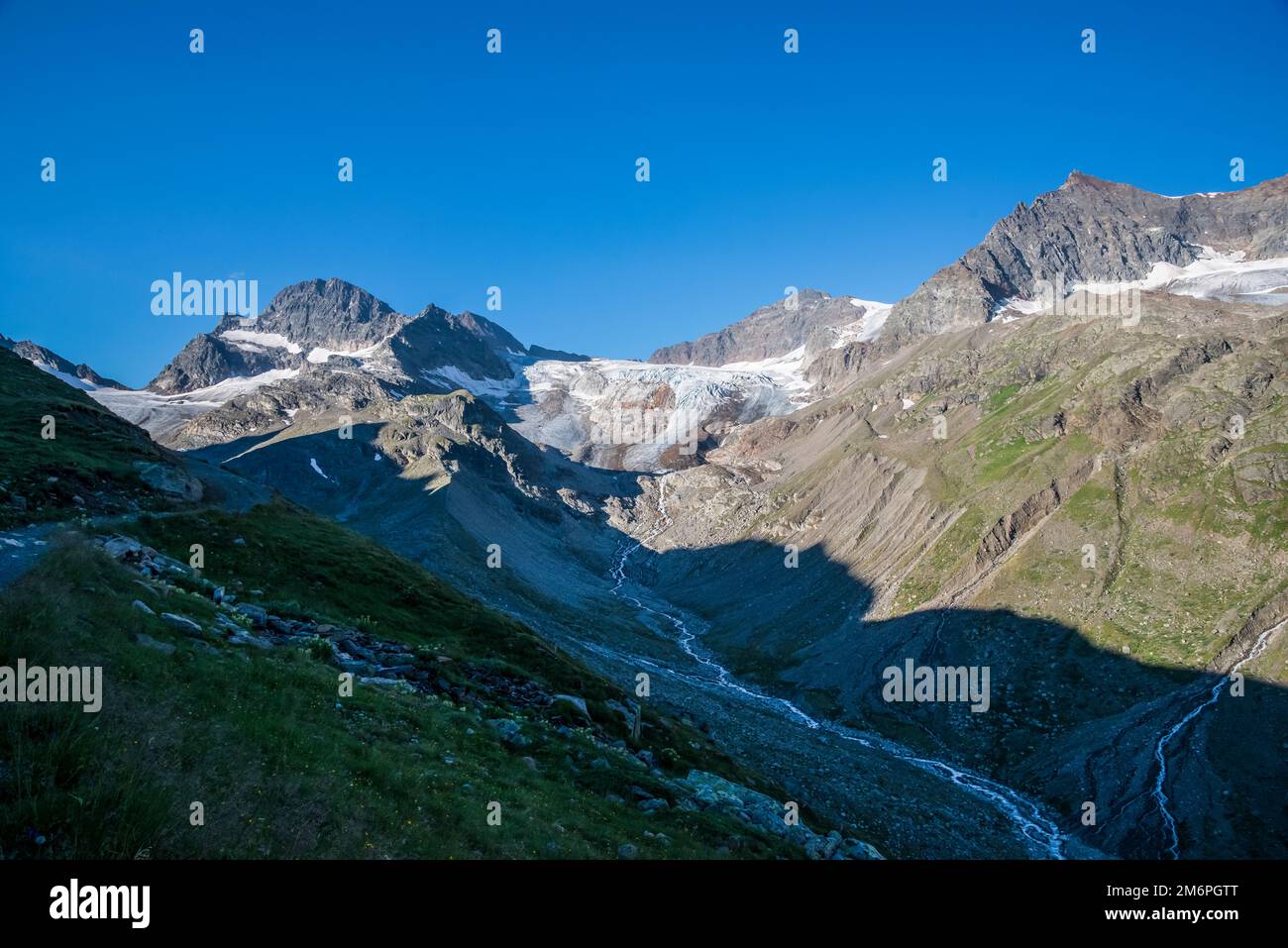 Immagine panoramica che si affaccia sulla valle dell'Ochsentaler verso Piz Buin 3213m, in alto a sinistra, condivisa con il confine internazionale austriaco con la Svizzera, non lontano dal rifugio Wiesbadener nel gruppo montuoso delle Alpi Silvretta, sopra il bacino di Bielerhoehe Stausee nel Tirolo austriaco. La capanna è spesso utilizzata dagli scalatori che desiderano salire Piz Buin, o le cime adiacenti del Corno Silvretta o delle Spitze Dreilander Foto Stock