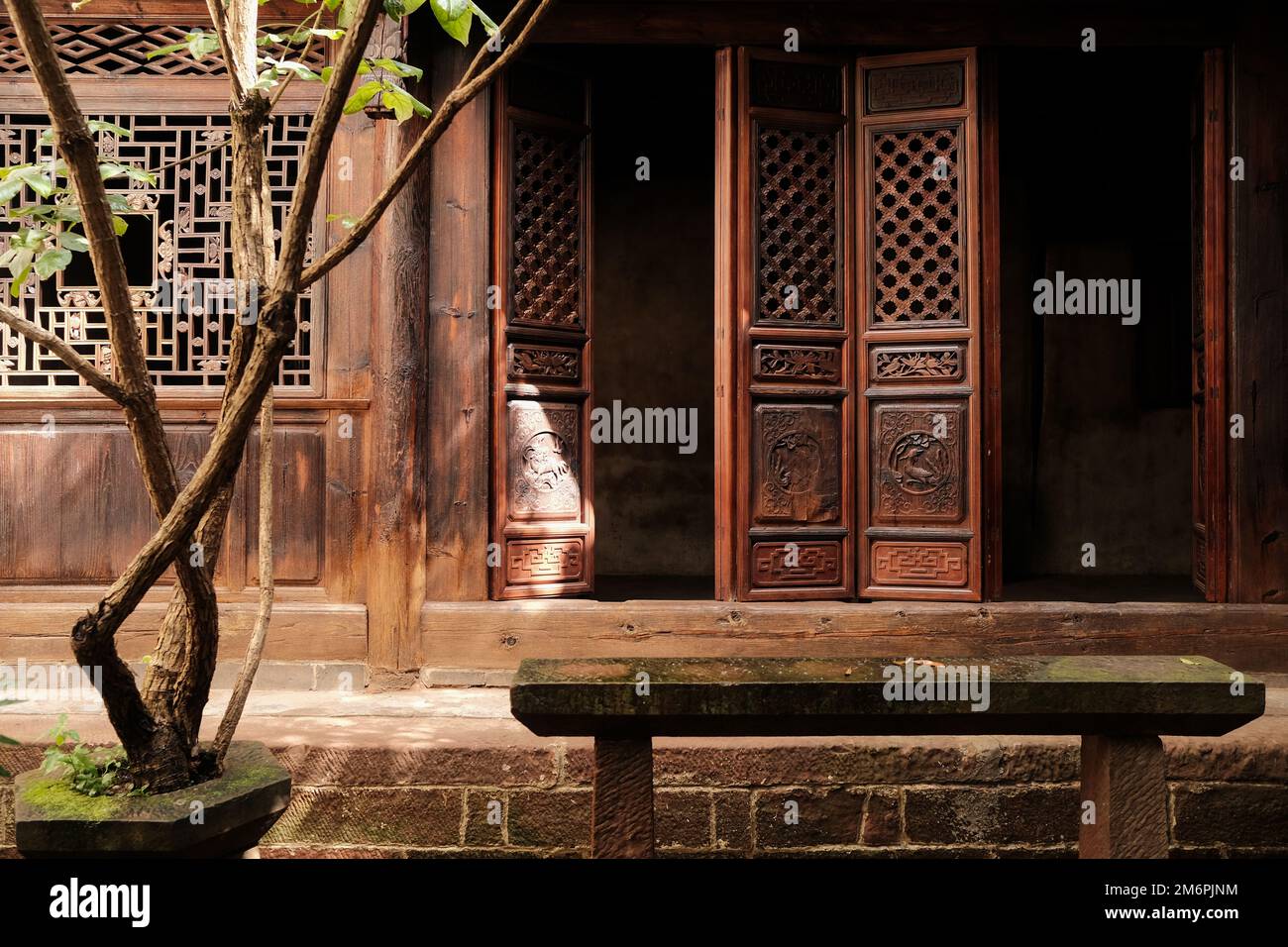 Tradizionale casa cinese cortile. Vecchia casa giardino con alberi. Schermi cinesi di legno texture sulla facciata della casa. Schermi in legno nel cortile. Foto Stock