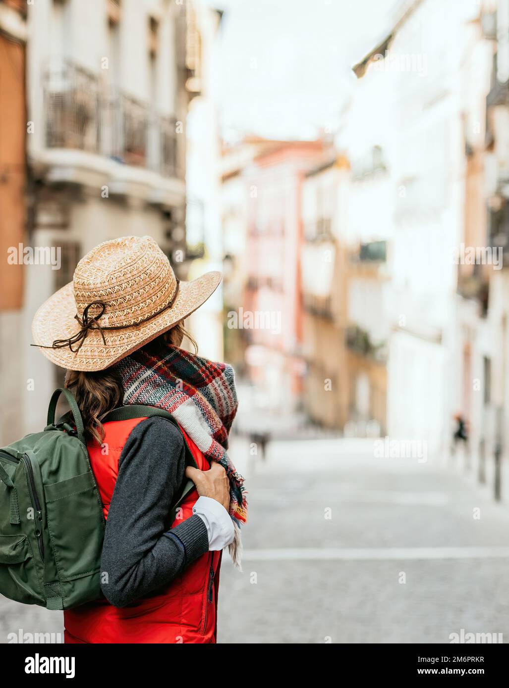 primo piano della donna con zaino e cappello sulla schiena, guardando i vecchi edifici di una città. concetto di turismo urbano in spagna. Foto Stock