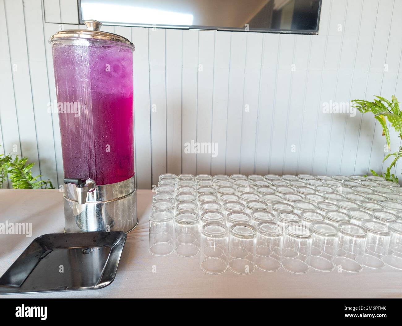 Bevanda a base di succo in un dispenser di bevande. Succo self-service in contenitore e bicchieri sul tavolo. Foto Stock
