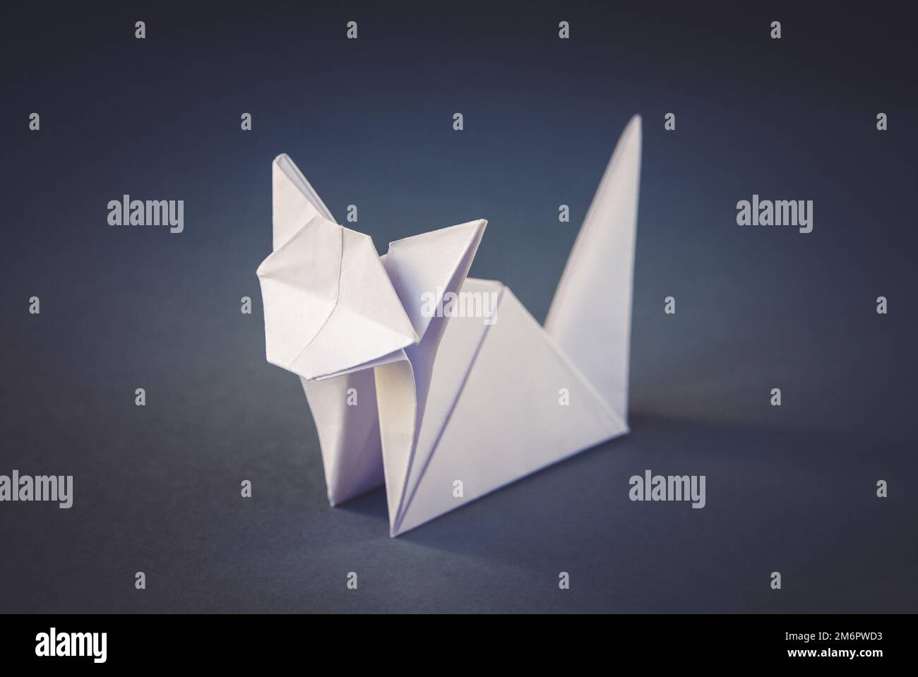 Carta bianca gatto origami isolato su uno sfondo grigio Foto Stock