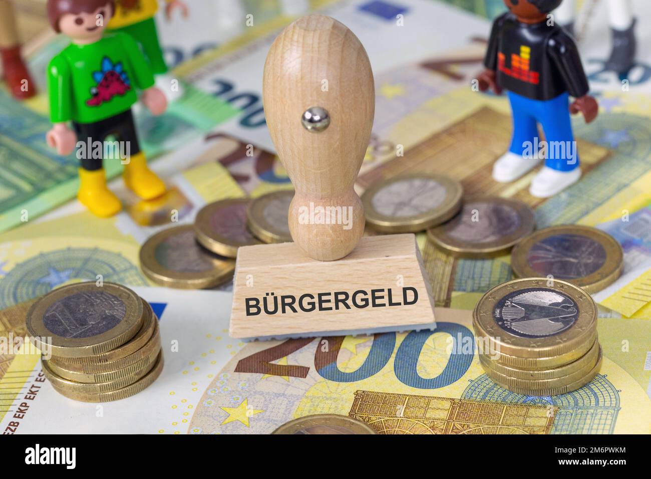 Symbolbild Bürgergeld: Stempel mit der Aufschrift Bürgergeld und Spielzeugfiguren von Playmobil auf Eurobanconoten Foto Stock