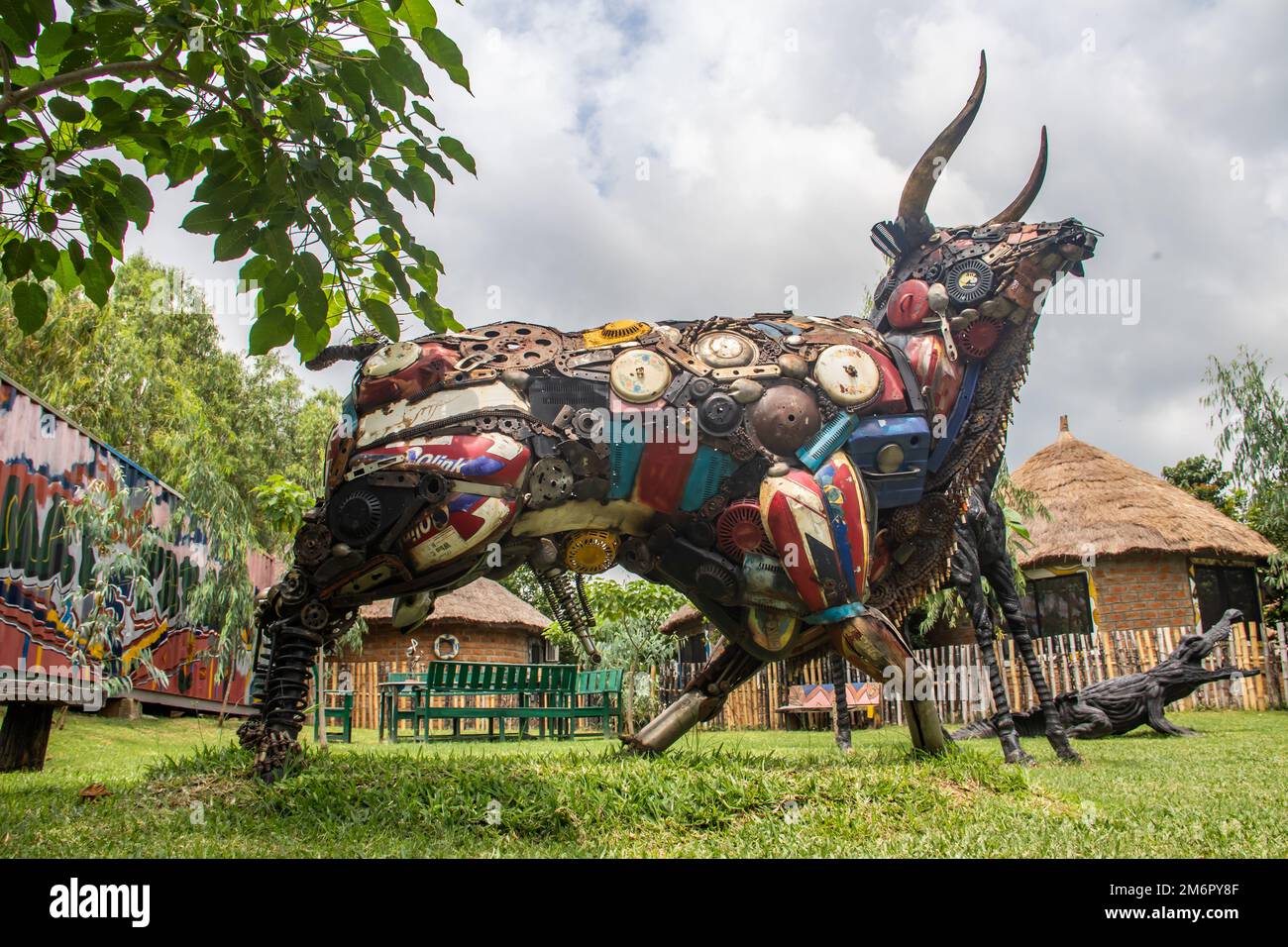 Sculture di animali colorate con corna lunghe si ergono su un prato accanto a un padiglione di paglia. Foto Stock