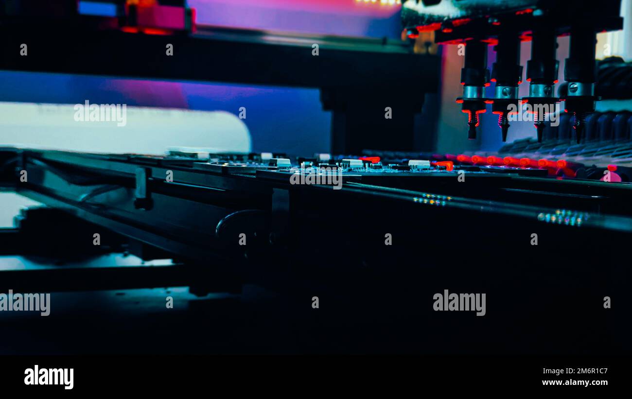 Produzione automatizzata di schede di sistema per computer mediante robot pick and place. Manipolatori di robot per assemblare chip di computer e schede di computer di sistema collocano componenti elettronici a bordo per il fissaggio. Foto Stock