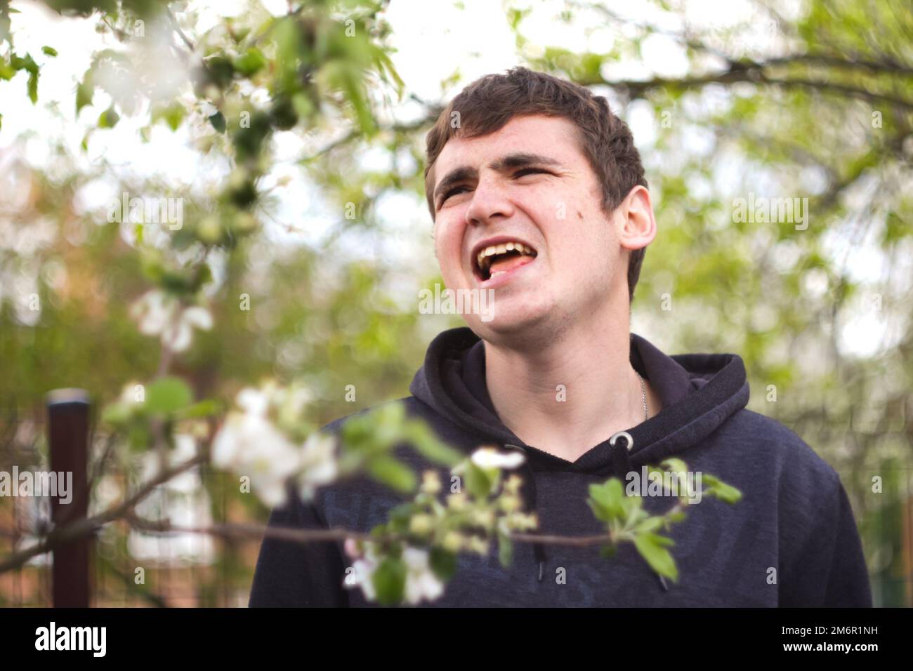 Uomo divertente nel giardino di primavera che canta all'esterno. Respira liberamente. Un uomo ha divertimento in natura. Uomo felice senza allergia. Concetto di allergia primaverile. Primavera Foto Stock