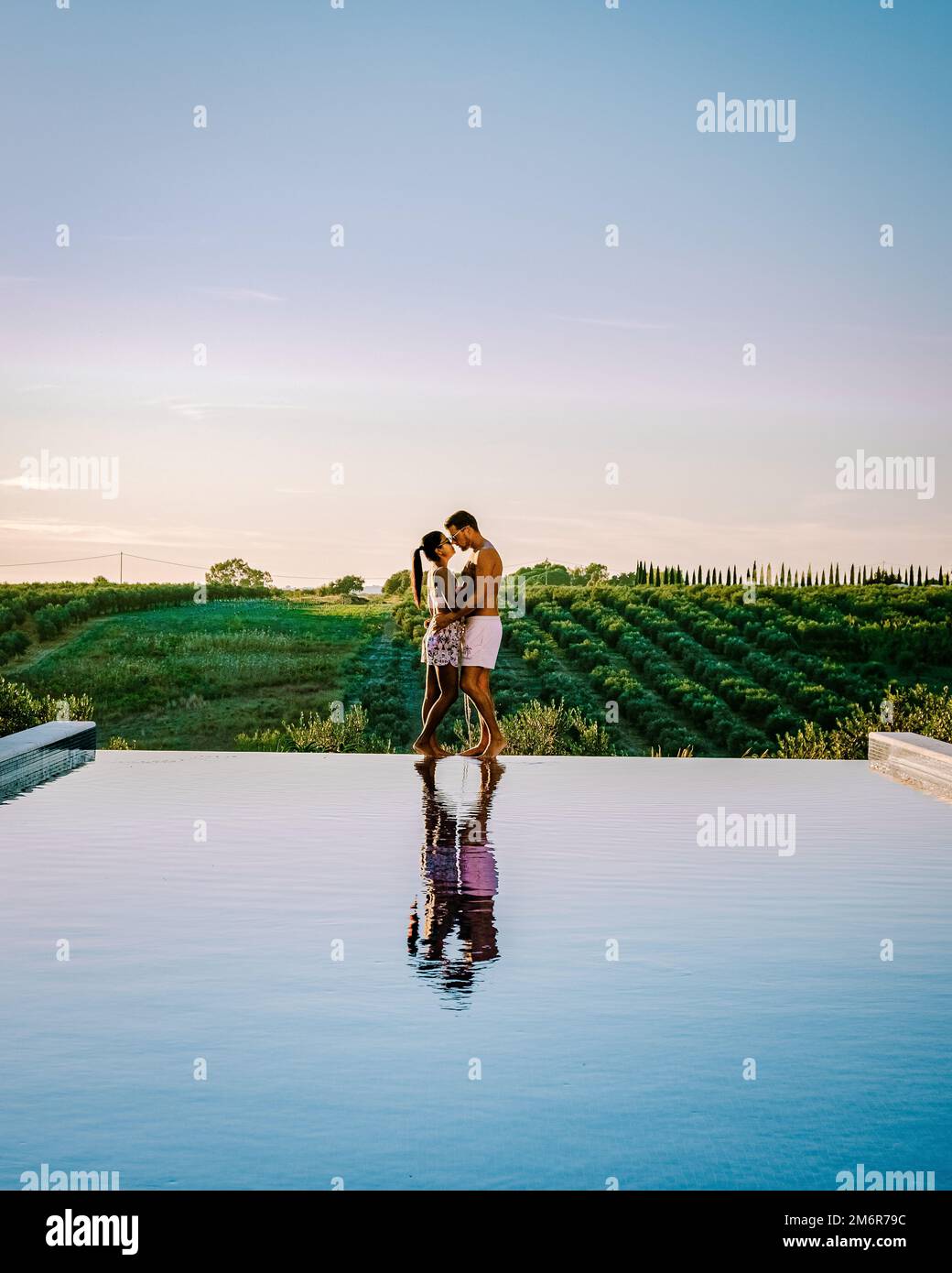 Coppia in vacanza in un resort di lusso in Sicilia durante il tramonto presso la piscina infinity in Sicilia Italia Foto Stock