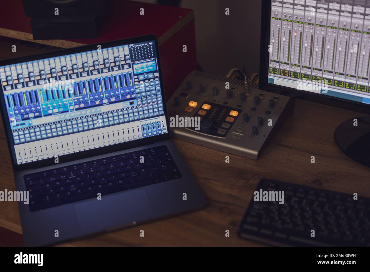 Primo piano attivato sullo schermo del computer portatile e del monitor con pannello di mixaggio su un tavolo in uno studio di trasmissione e registrazione del suono Foto Stock