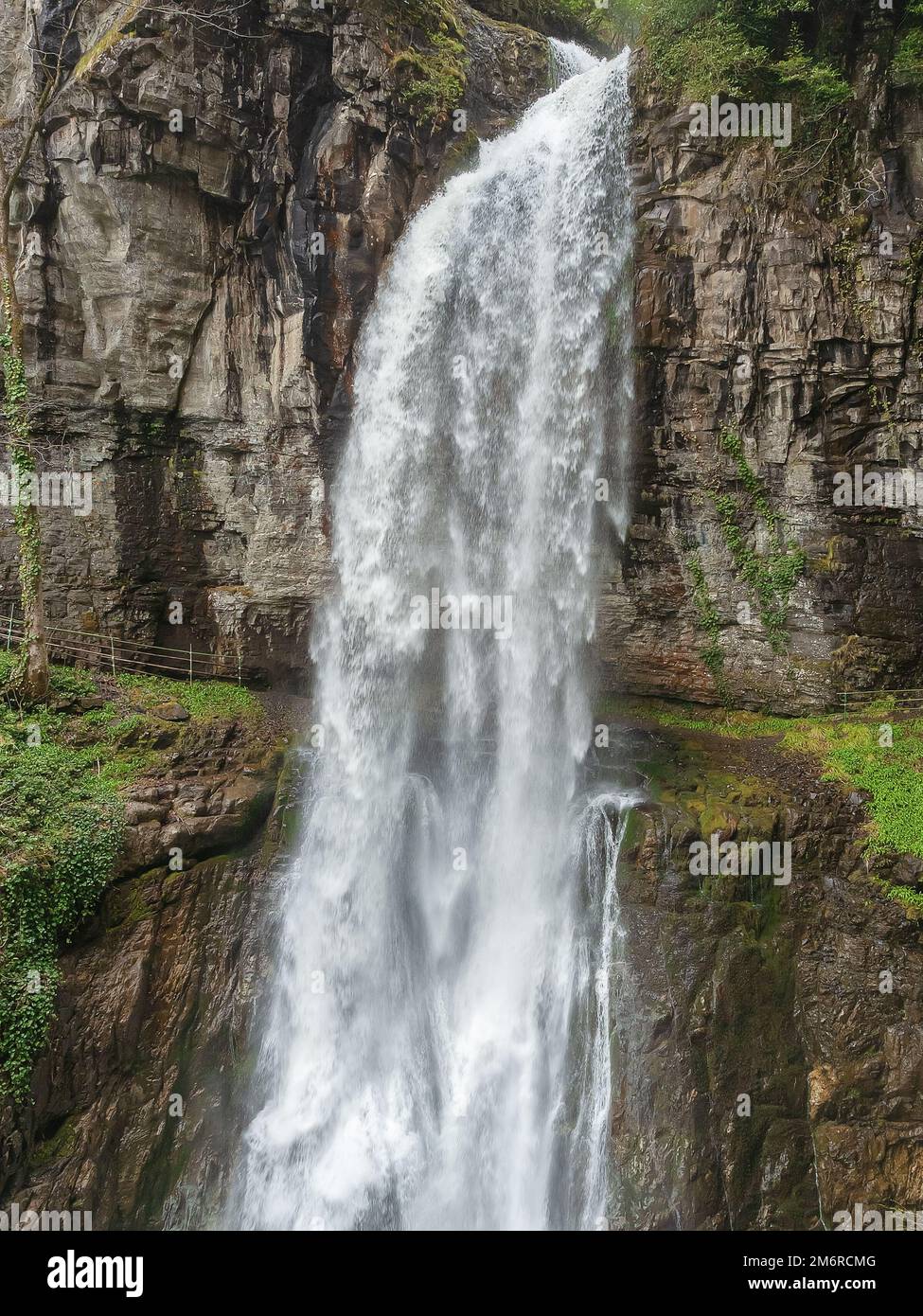 Gola di montagna rocciosa con una cascata enorme. Una cascata gigante scorre in una gola rocciosa. Sfocatura del movimento Foto Stock