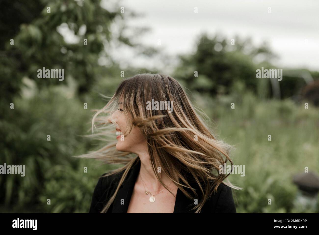 Giovane donna ridente in ritratto, 25, con capelli volanti Foto Stock