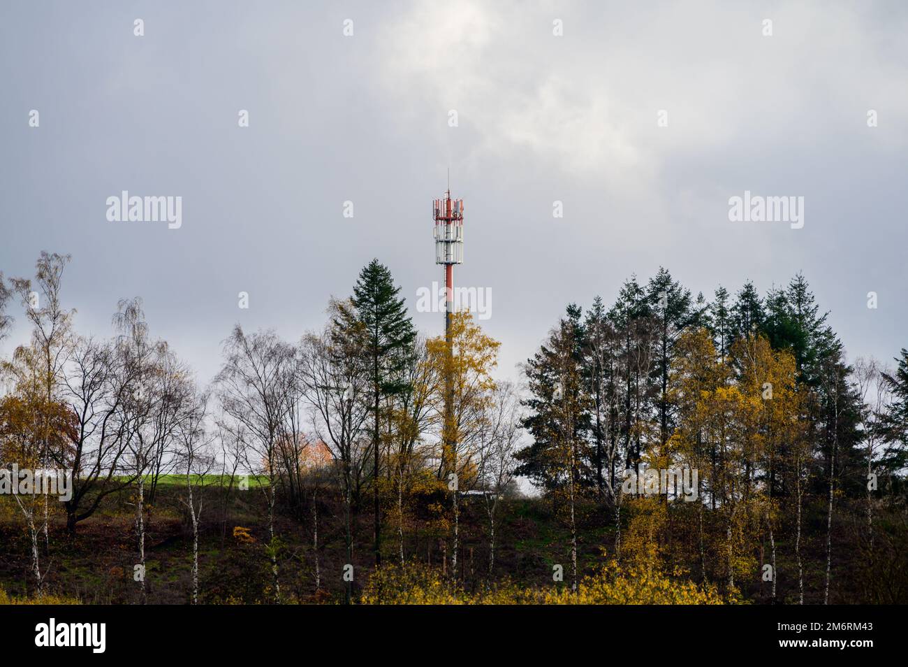 Alto rosso e bianco telecomunicazioni mobile e 5G torre cellulare sulla collina in autunno Foto Stock