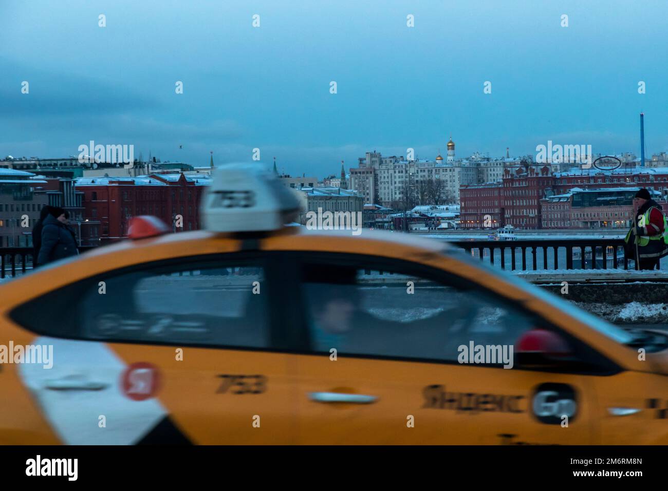 Mosca, Russia. 5th gennaio 2023. Un taxi giallo con l'iscrizione 'Yandex Taxi' corre sul Ponte di Crimea sullo sfondo di una vista panoramica del centro di Mosca, Russia Foto Stock
