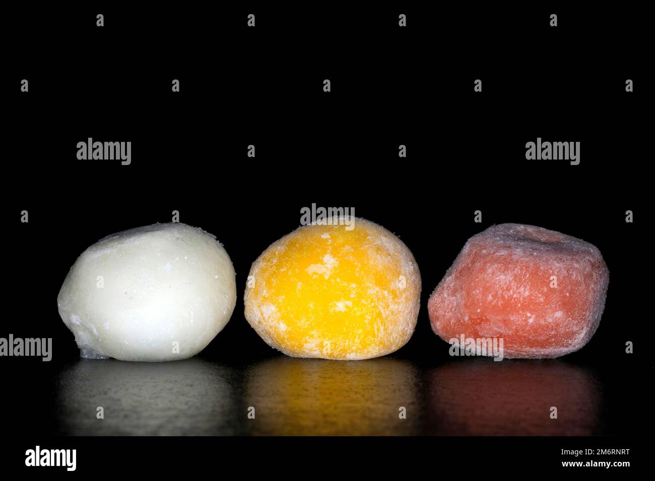 Gelato giapponese mochi ripieno di yuzu, mango e fragola, fotografia alimentare con sfondo nero Foto Stock