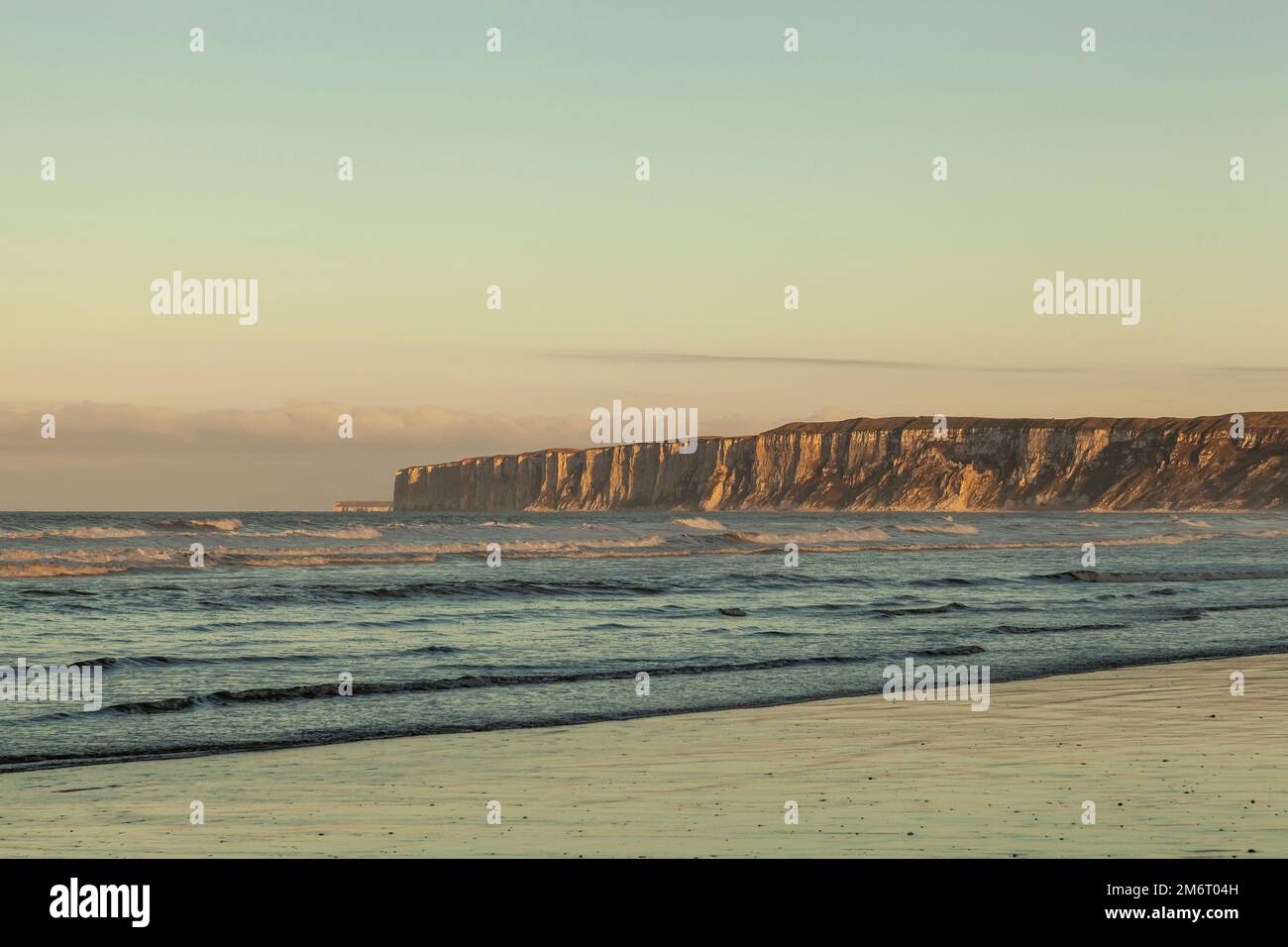 Il sole si trova sulle torreggianti scogliere di Flamborough Head, viste da Hunmanby Sands, Filey, North Yorkshire Foto Stock