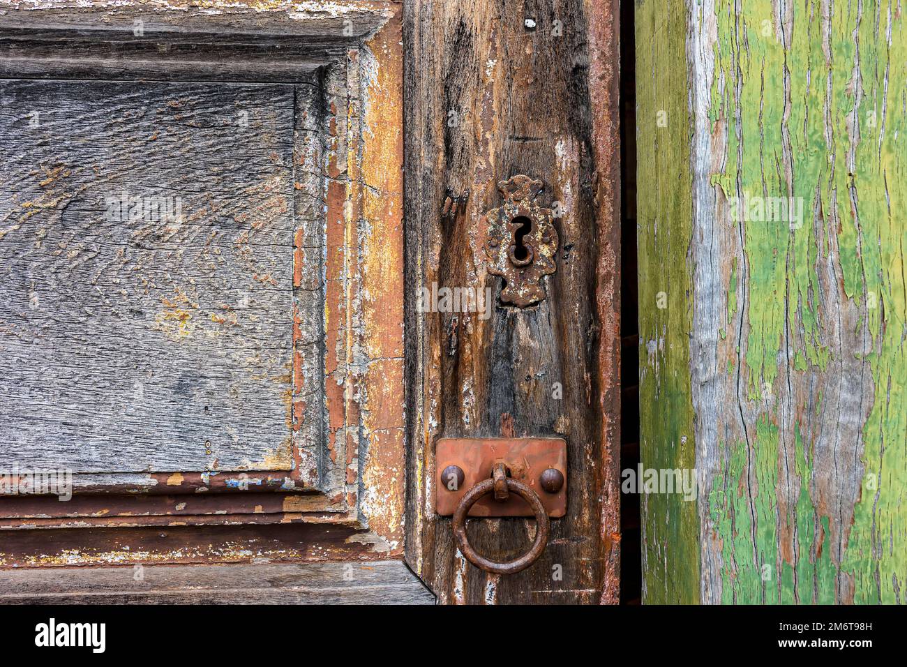 Antica porta di legno e serratura deteriorata dal tempo e ruggine in una casa di stile coloniale Foto Stock