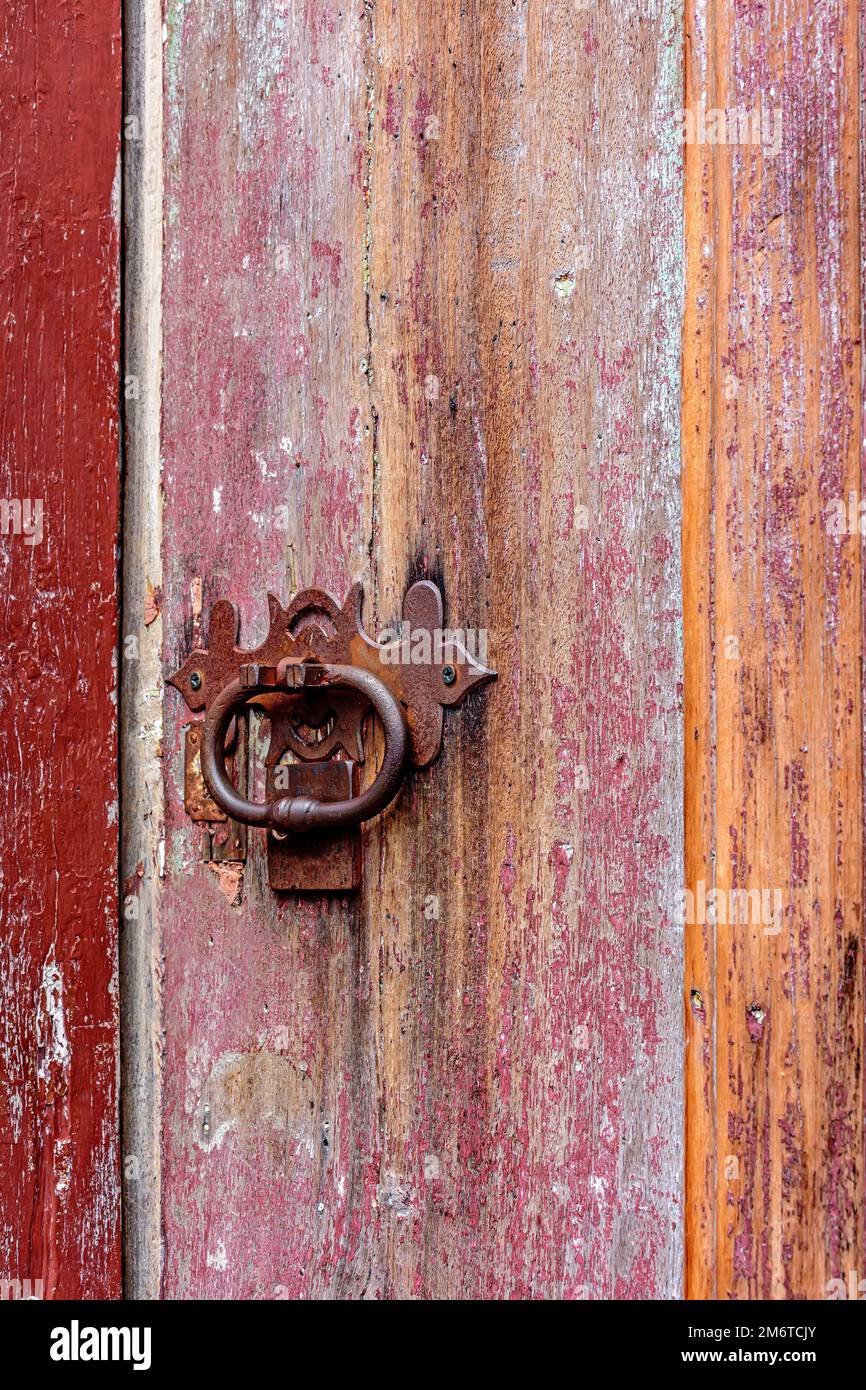 Antica porta di legno colorato e serratura deteriorata dal tempo e ruggine in una casa coloniale Foto Stock