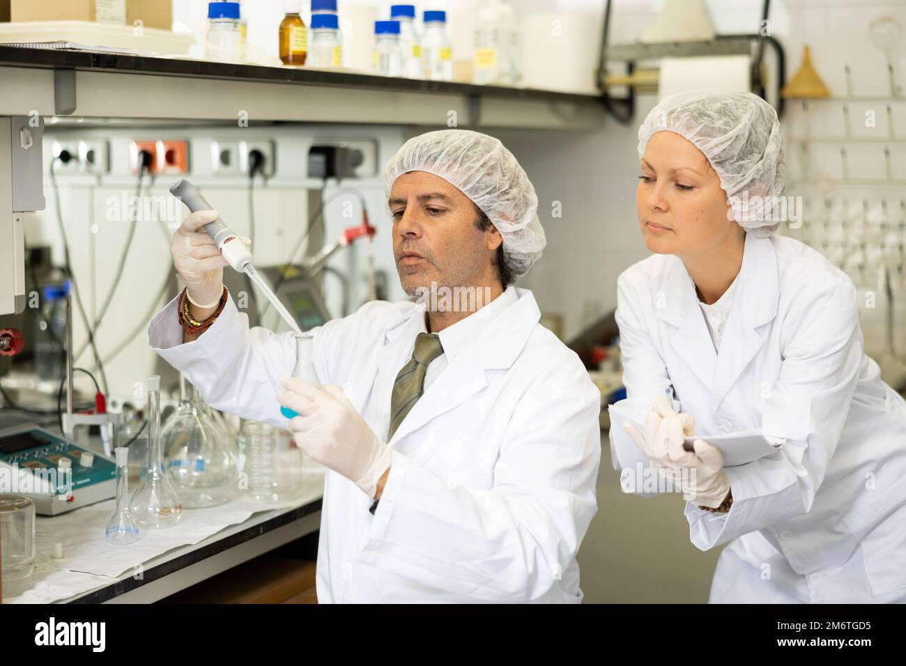 Gli scienziati chimici dell'uomo e della donna conducono gli esperimenti nel laboratorio Foto Stock