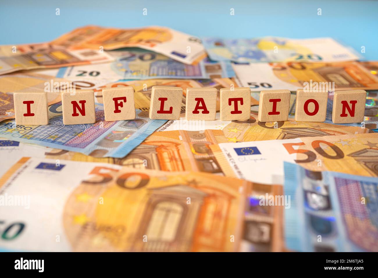 La parola inflazione scritta su tasselli di legno sullo sfondo delle banconote in euro Foto Stock