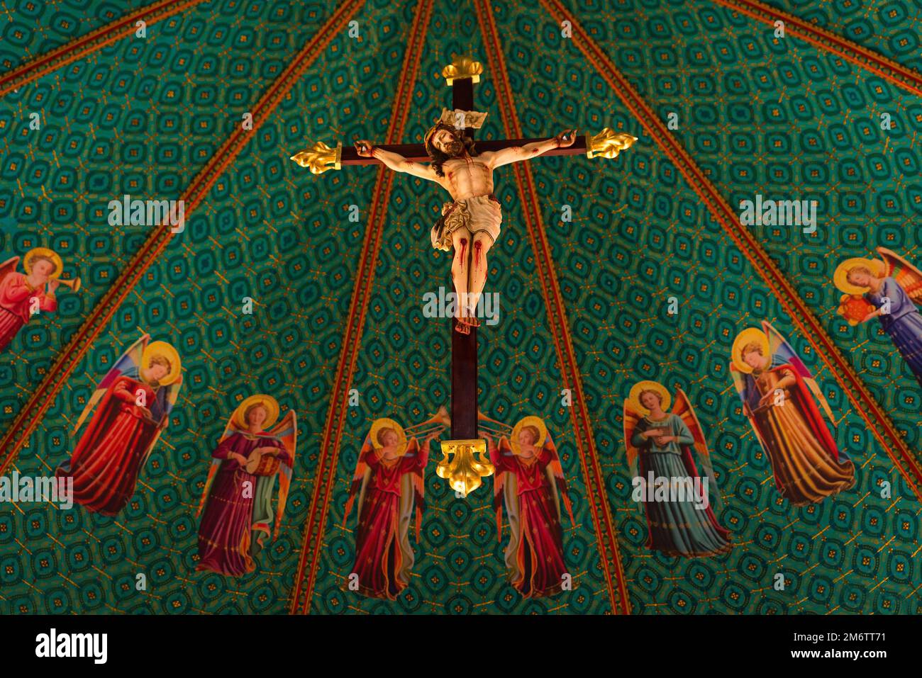 Scultura di Gesù Cristo crocifisso appeso su una croce con immagini di santi intorno Foto Stock