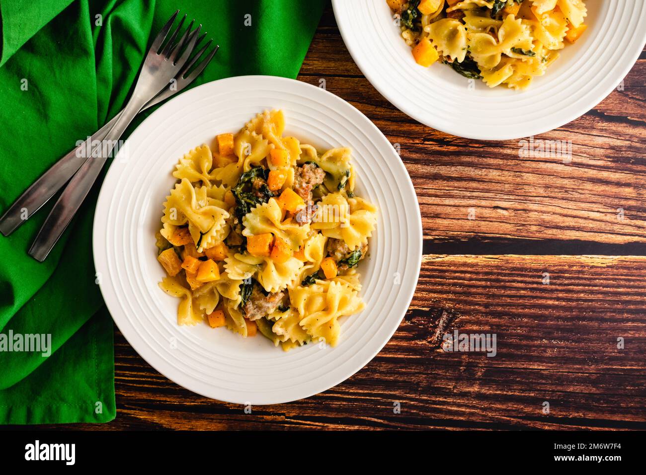 Ciotole di zucca cremosa arrosto Pasta con salsiccia e spinaci: Vista dall'alto del cibo di comfort fatto con farfalle e zucca invernale Foto Stock