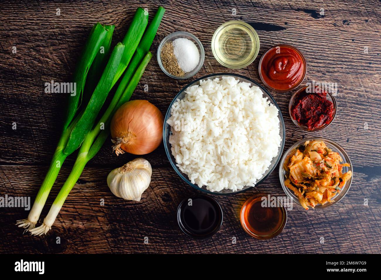 Riso fritto kimchi ingredienti su una tavola rustica di legno: Riso cotto, cavolo fermentato, e altri ingredienti e condimenti Foto Stock