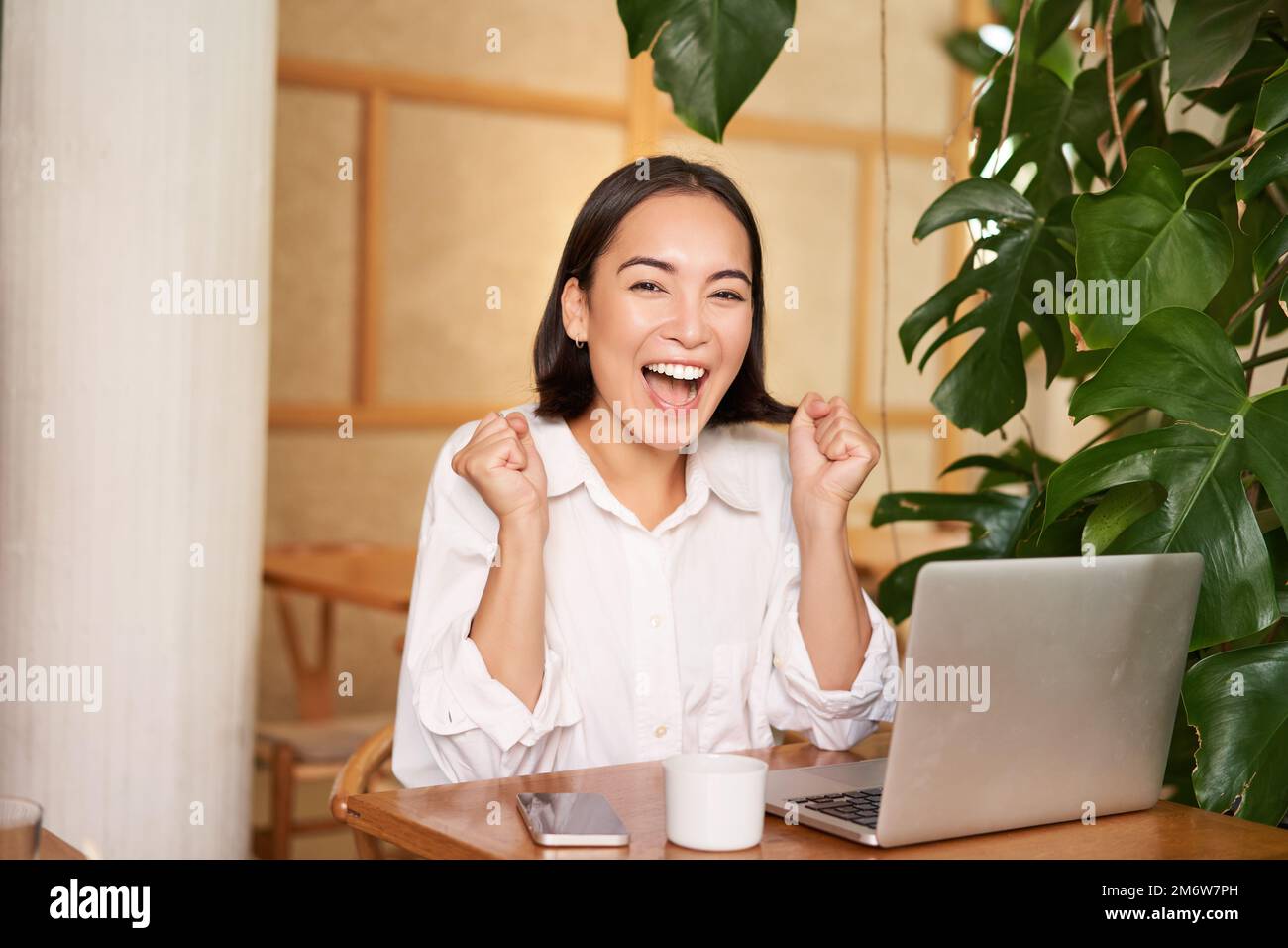 Elegante donna d'affari in piedi in ufficio con tavoletta digitale eccitata  donna d'affari asiatica che alza le mani per congratularsi mentre lavora al computer  portatile in ufficiox9