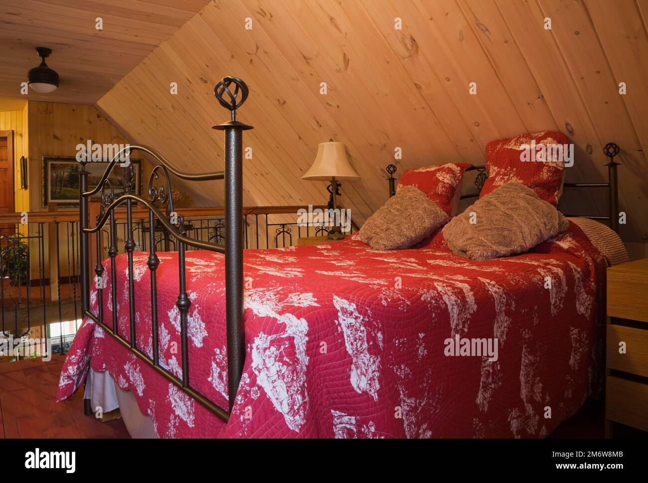 Letto queen size a baldacchino con testiera e poggiapiedi in ferro battuto nella camera da letto principale al piano superiore all'interno di una casa in legno. Foto Stock