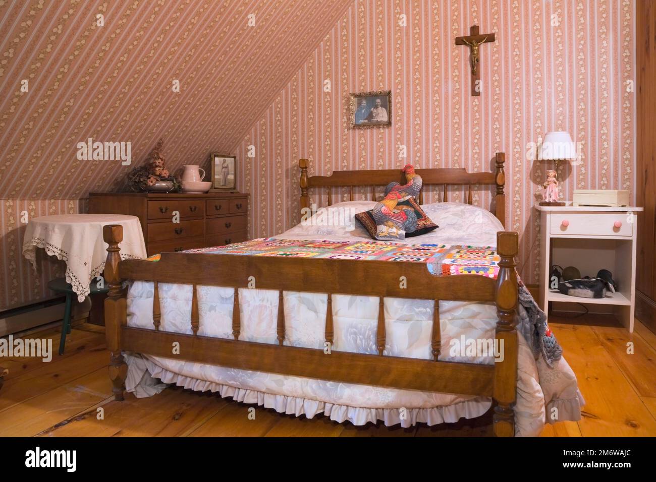 Letto queen size con struttura in legno e testiera in legno nella camera da letto al piano superiore, all'interno di una casa in legno ricostruita nel 1980. Foto Stock