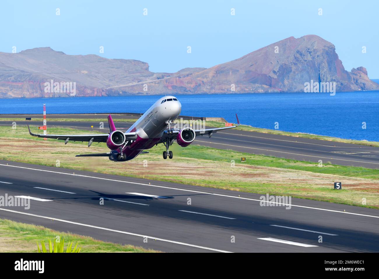 Decollo dell'aeromobile Wizz Air Airbus A321. WizzAir Aircraft A321 durante il decollo dall'aeroporto di Madeira (aeroporto di Funchal) con paesaggio dietro. Foto Stock