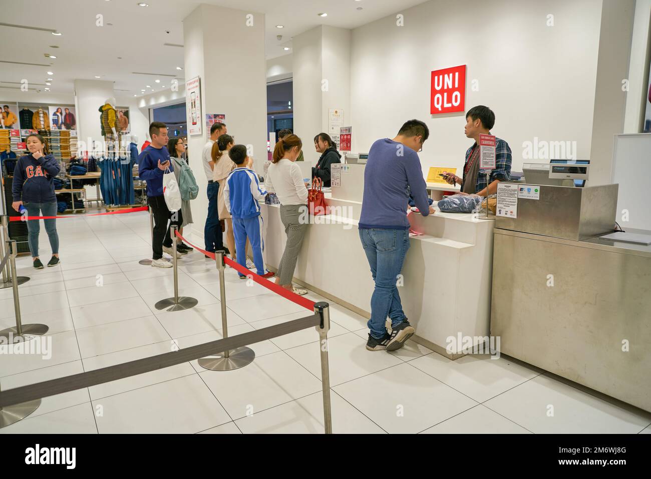 SHENZHEN, CINA - CIRCA NOVEMBRE 2019: Le persone pagano al banco di cassa nel negozio Uniqlo. Uniqlo è un designer, produttore e rivenditore di abbigliamento casual giapponese. Foto Stock
