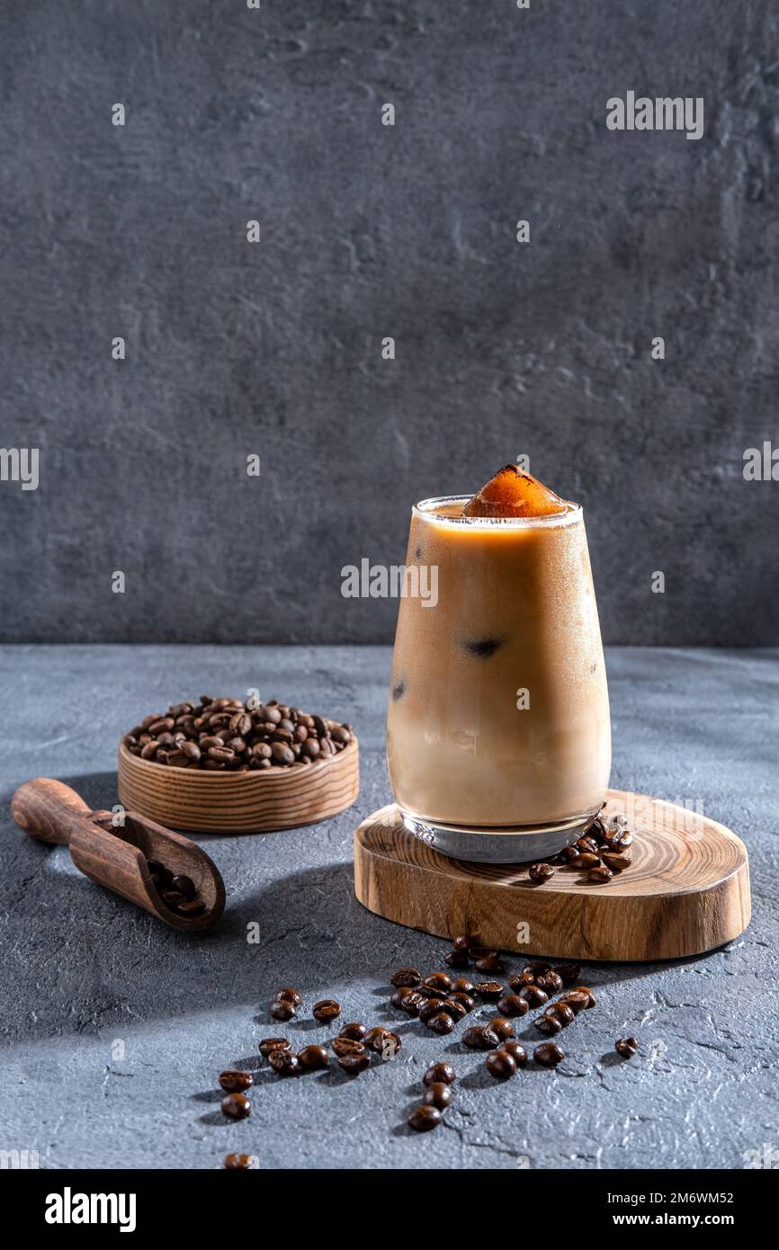 Gelato in un bicchiere alto con panna versata e chicchi di caffè. Bevanda fredda a base di caffè su sfondo scuro con spazio per le copie. Foto Stock