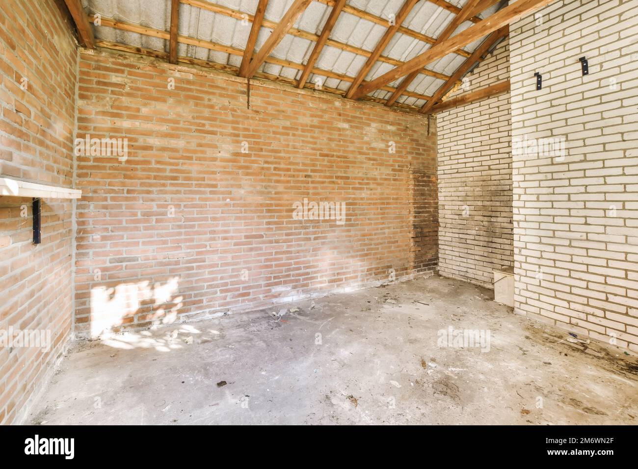 una stanza incompiuta con pareti in mattoni e travi in legno sul soffitto in una nuova casa in costruzione progetto foto stock Foto Stock