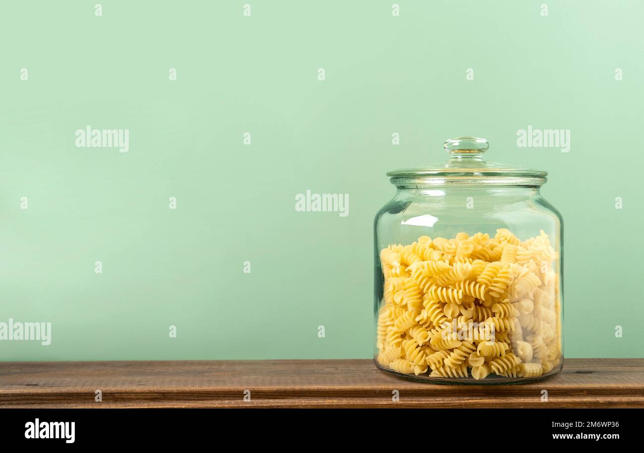 Fusilli in vaso di vetro su fondo verde. Nessun deposito di rifiuti, senza plastica. Foto Stock