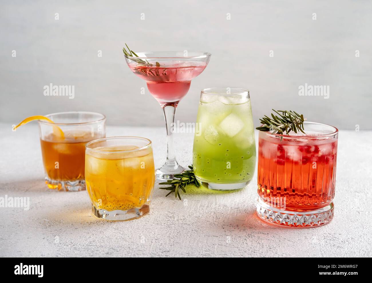 Cinque cocktail estivi colorati in bicchieri su un tavolo bianco. Assortimento di bevande fresche estive. Cocktail sangria rosa e rossa, o Foto Stock